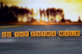 Row of wooden blocks spelling out extra mile